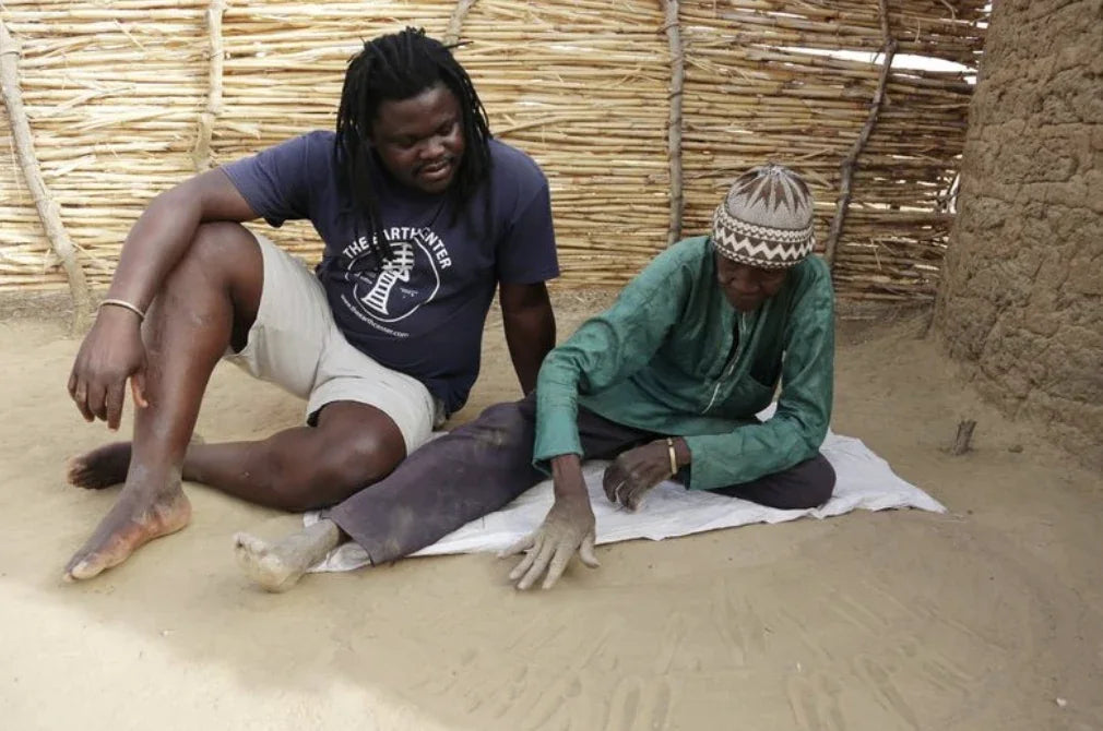 Two Indigenous African priests seated together on the sand