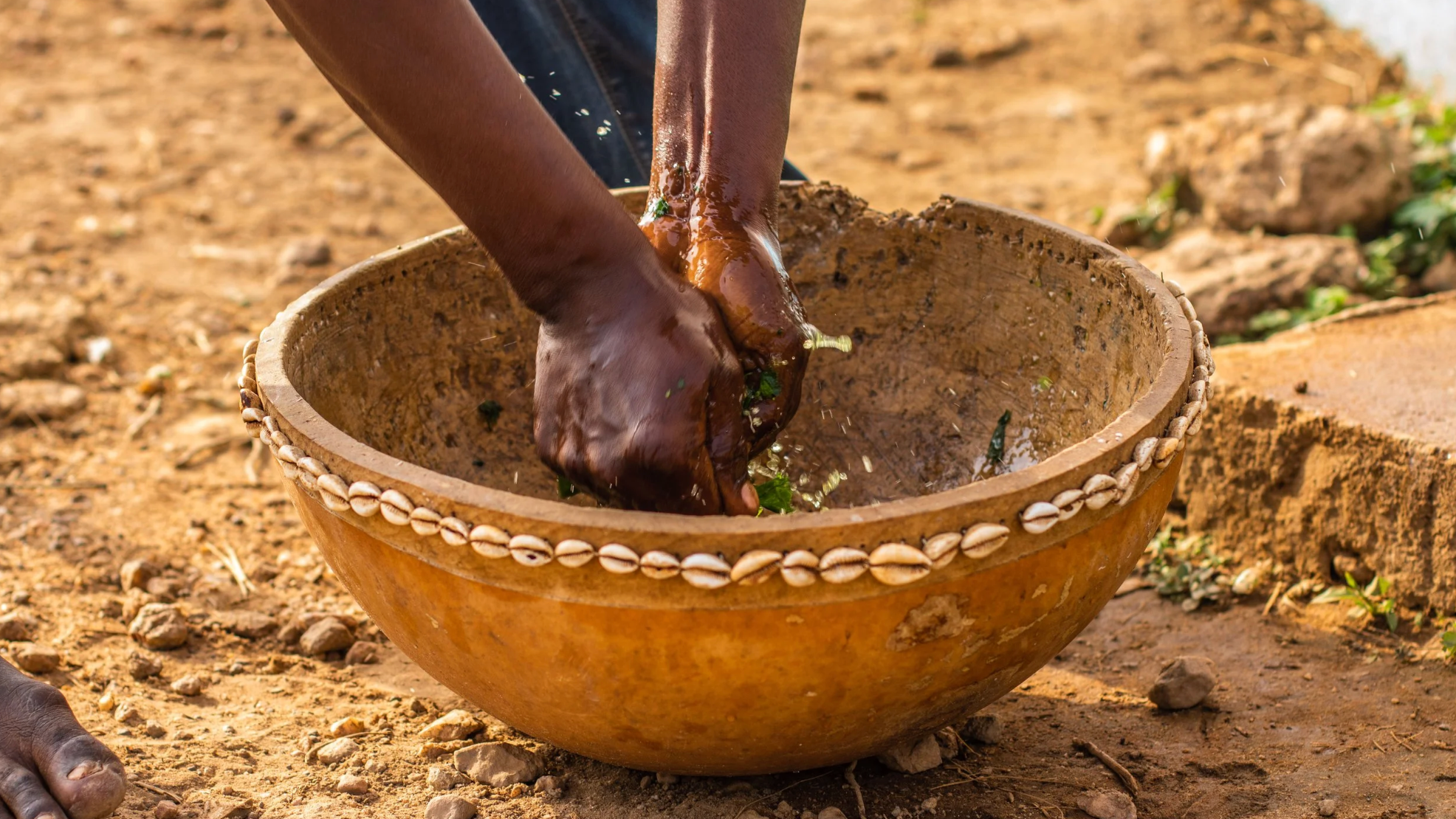 Traditional preparation of fresh herbs in a cowrie-decorated bowl