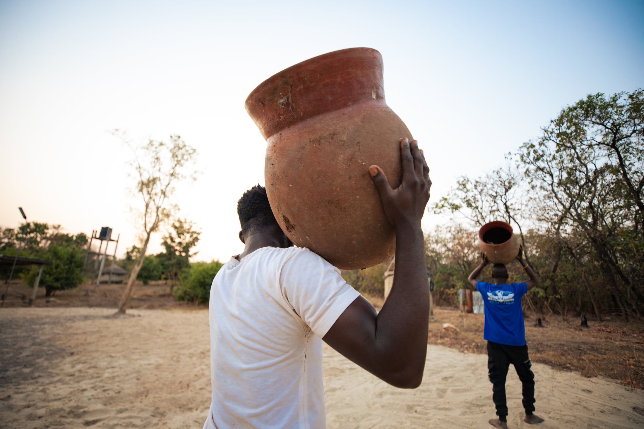 Community members carrying traditional vessels through the landscape